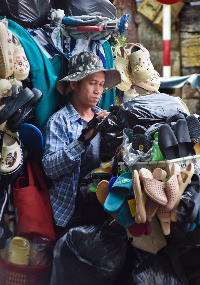 Home Street vendor in Nha Trang, Vietnam selling assorted footwear in a bustling outdoor market.